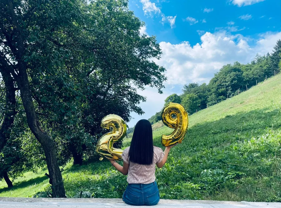 Gold birthday balloons on the hillside, with a nature view